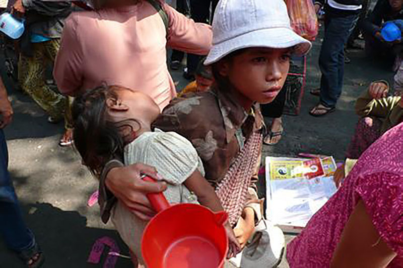 図10.6 | ベトナムの路上で物乞いをする少女が、幼い子供を抱きかかえながら、食べ物を求めています。(Credit: Augapfel/flickr)